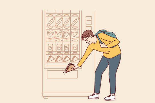 Man Student Bends Down To Pick Up Sandwich While Shopping For Lunchtime Snack From Vending Machine. Shopper Uses Automatic Vending Machine To Whet Appetite After College Or University Classes 