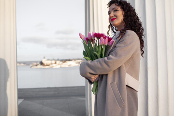 the portrait of 35 years old woman is walking with a bouquet of flowers in the spring streets of...