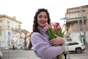 35 years old woman is walking with a bouquet of flowers in the spring streets of the city