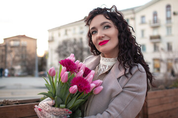 35 years old woman is walking with a bouquet of flowers in the spring streets of the city