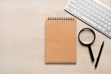 Blank notebook, pen, magnifier and keyboard on wooden background. World Poetry Day celebration