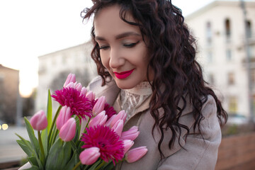 35 years old woman is walking with a bouquet of flowers in the spring streets of the city