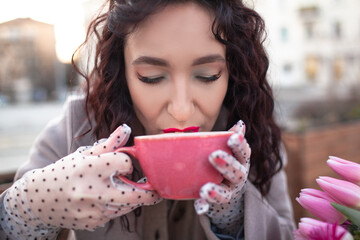 35 years old woman is drinking coffee or tea in cafe with a bouquet of flowers in the spring...