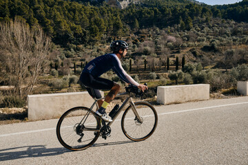 Obraz premium A professional sports cyclist riding fast uphill.A man riding a gravel bike.Sport motivation. Alicante, Spain