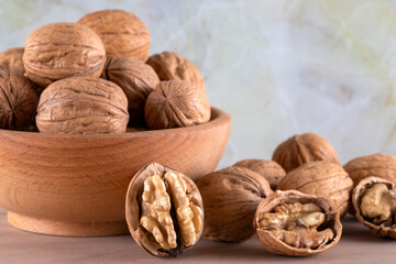 Walnut kernels and cracked walnuts on wooden background, front view