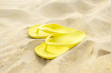 Plakat Yellow flip-flops on sand. Sandals on the beach