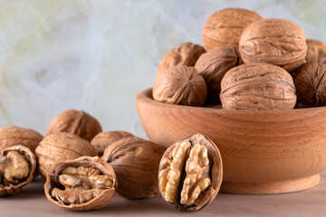 Walnut kernels and cracked walnuts on wooden background, front view
