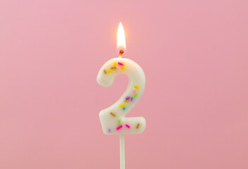 Burning  birthday candle on pink background, number 2