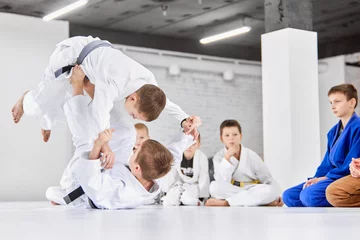Fotobehang Dynamic portrait. Boys, children in white kimono training, practising judo, jiu-jitsu exercises indoors. Attention. Concept of martial arts, combat sport, sport education, childhood, © master1305