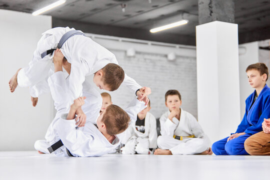Dynamic portrait. Boys, children in white kimono training, practising judo, jiu-jitsu exercises indoors. Attention. Concept of martial arts, combat sport, sport education, childhood,