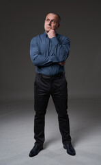 Pensive mature businessman on gray