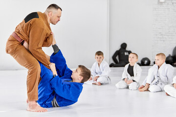 Teacher, professional judo, jiu jitsu coach training kinds, boys, showing exercises. Attention,...
