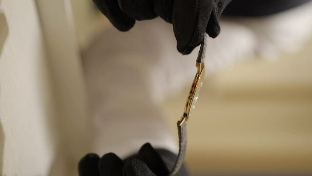 VERTICAL Salesperson gloved hands holding luxury gold Piaget wristwatch close up