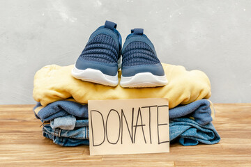 Stack of old baby children clothes,sneakers sorted into Donate categories.Donation,volunteering...