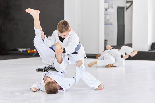 Boys, children in white kimono training, practising judo, jiu-jitsu exercises indoors. Concept of martial arts, combat sport, sport education, childhood, strength, hobby - Powered by Adobe