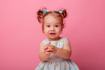 baby girl in a beautiful dress sitting on a pink background