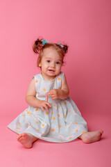 baby girl in a beautiful dress sitting on a pink background