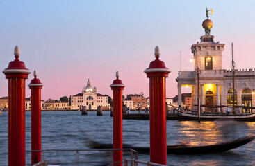 Venezia. Punta della Dogana da Mar con bricole e gondola in transito verso Le Zitelle al Tramonto