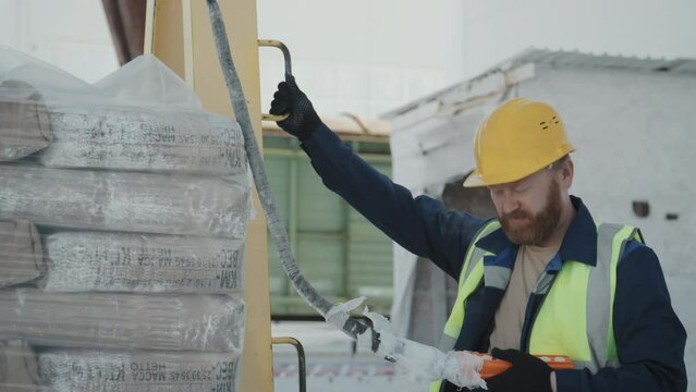 Caucasian male factory worker using lifting hoist to transport heavy bags with materials