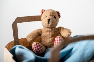 Paper bag with used clothing and bear toy to donate on wooden table. Reuse. Close up
