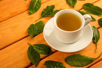 A glass cup of green tea, tea leaves  on wooden background
