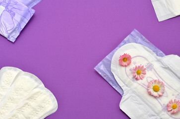 feminine hygiene products and flowers on a purple background, space for an object