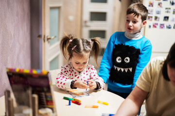 Mother and children decorating art with glitter decor.
