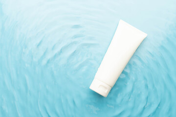 Blank white squeeze bottle plastic tube on blue water surface wtih waves. Packaging of moisturizing cream, cleansing gel or hydrating body lotion. Spa and skincare product branding mock up.