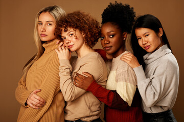 Studio shot of multicultural friends posing isolated on brown background and looking at the camera.