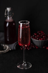 Cranberry mimosa cocktail on dark background. Cocktail garnished with sugar and fresh cranberries.