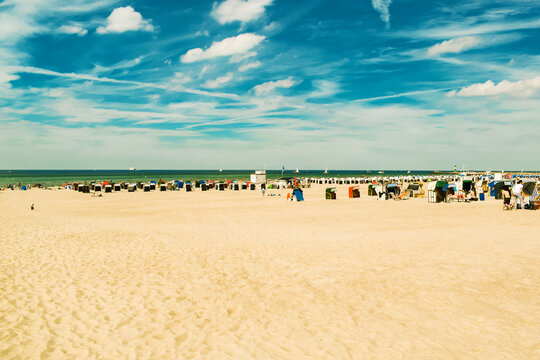 Bbeach sand, blue sky with clouds, beach chairs. People are sunbathing. The beach of the Baltic Sea, Germany resort.