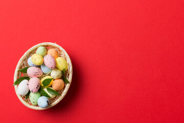 Colorful Easter eggs in wicker basket against colored background, closeup. top view with copy space