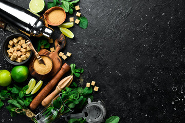 Mojito preparation: shaker, lime, mint and ice. On a black stone background. Top view.