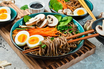 Buckwheat soba pasta with egg, mushrooms and microgreens. On a gray stone background. Side view....
