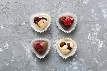 chocolate sweets in the form of a heart with fruits and nuts on a colored background. top view with space for text, holiday concept