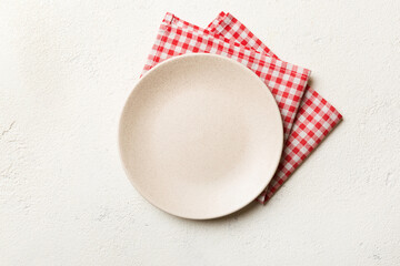Top view on colored background empty round white plate on tablecloth for food. Empty dish on napkin with space for your design - obrazy, fototapety, plakaty