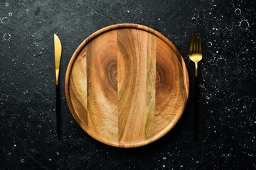 Wooden plate and cutlery. Table setting. Top view. On a stone dark background.