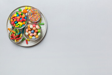 Fototapeta na wymiar Multicolored candies in a bowl on a colored background. birthday and holiday concept. Top view with copy space