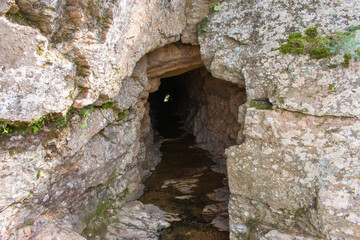cave in rocky mountain with river on the floor