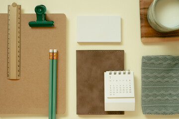 Office supply, stationery. Brown notebook, calendar, cup of milk, pencil, ruler, clip, pouch, memo pad on yellow desk background. flat lay, top view