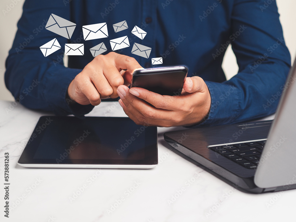 Poster businessman using a smartphone receives a new message with email icons while sitting at the table