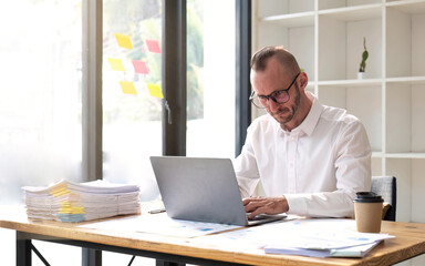 Young business man working at office with laptop and papers on desk
