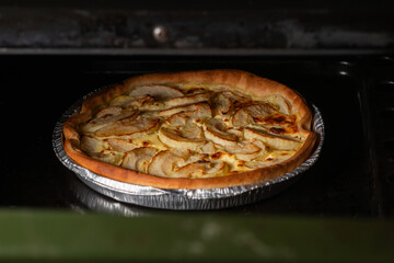 Pie with apples in the oven. Delicious round yellow veggie pie with sliced apples.