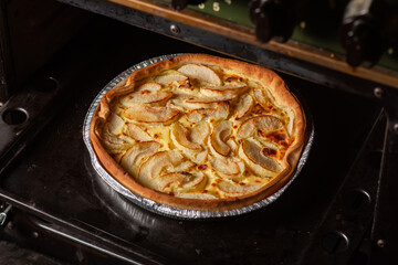 Pie with apples in the oven. Delicious round yellow veggie pie with sliced apples.