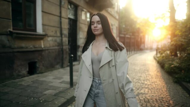 Beautiful Woman Wearing Fashionable Beige Trench Coat Outdoors. Female Stylish Model Walking City Street