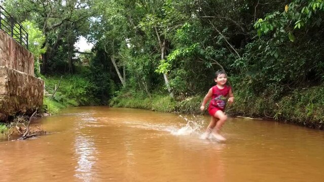 hispanic boy running down the river stream in Paraguay.