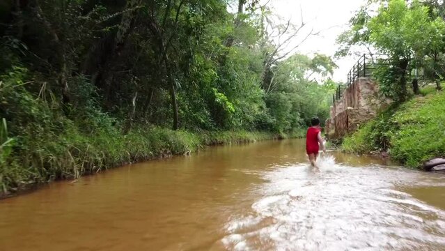 Young boy running down the river in Paraguay, South America.
