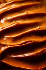 Creamy toffee dulce de leche caramel background texture close up view food art. Curls of caramel. Texture.