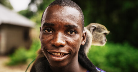 Close Up Portrait of an Authentic African Man Carrying a Little Monkey Looking at the Camera and...