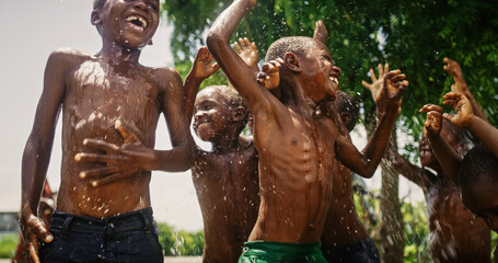 Group of African Kids Jumping and Laughing when Water Gets Poured on Them. Happy and Innocent Black...